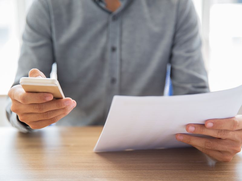 Uomo che legge un documento e invia un messaggio