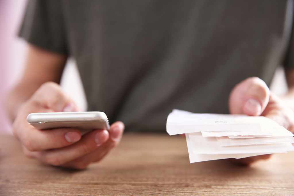 Mani che tengono uno smartphone e una quietanza di pagamento