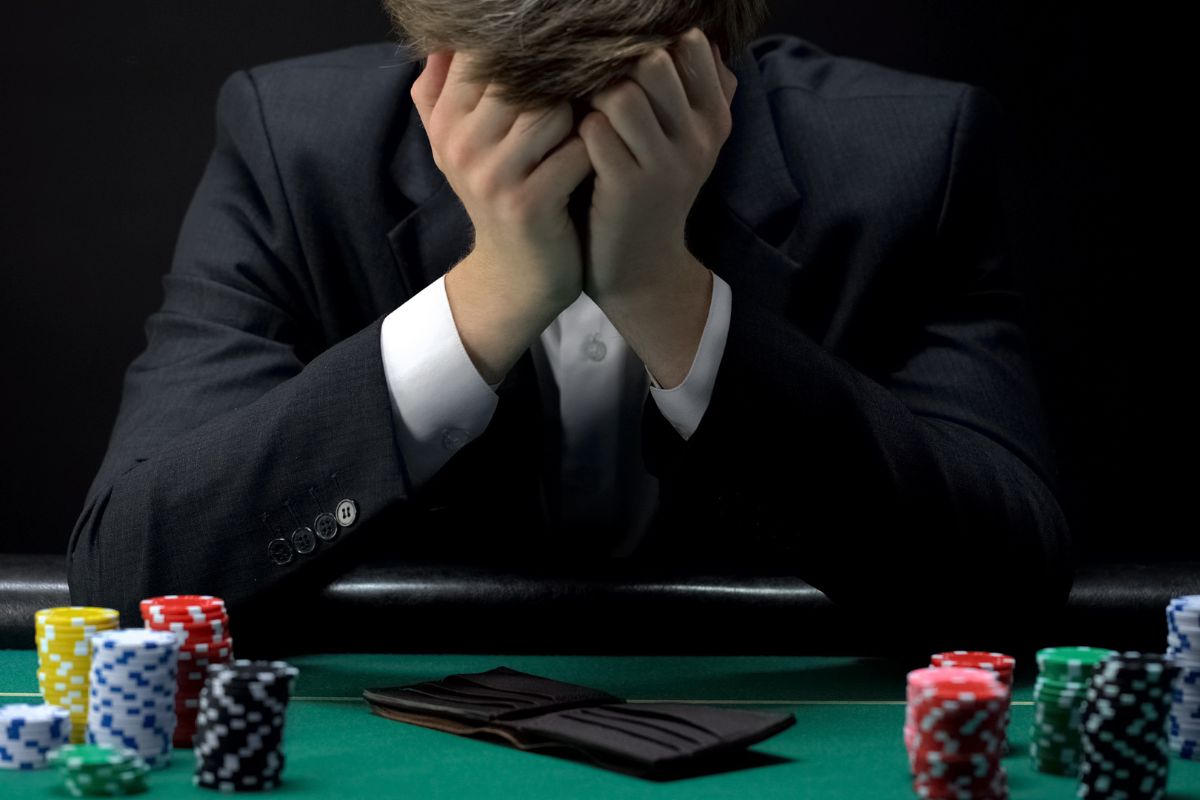 Giovane uomo d'affari disperato dopo aver perso a poker in un casinò, simbolo della dipendenza dal gioco d'azzardo e dei rischi dei debiti di gioco.